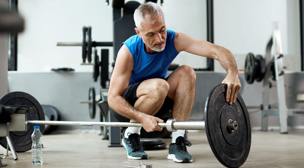 Why Lifting Weights Is the Maximum Tough Anti-Ageing Hack for Males elderly man placing weights on a barbell.jpg