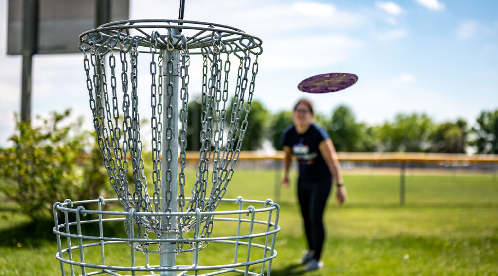 The Disc Golfing Coaching Information: Construct Energy, Refine Mechanics, and Throw Farther female disc golfer throwing the frisbee into the hole.jpg