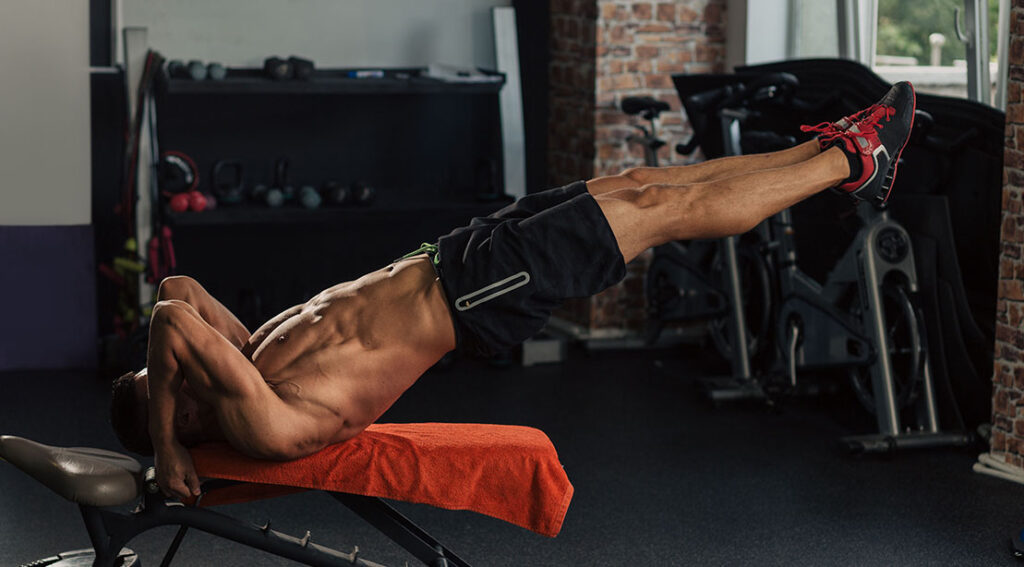 muscular fit and athletic man with a solid six pack performing bruce lees dragon flag exercise .jpg