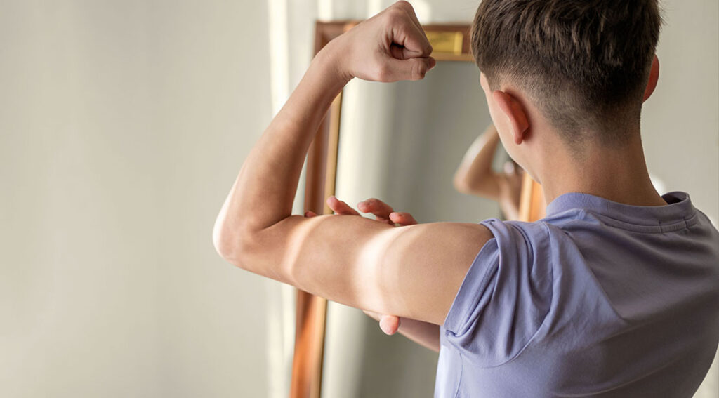 teenage boy flexing his biceps in the mirror.jpg