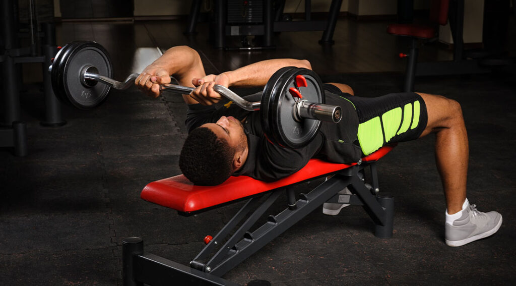 young athletic muscular man performing a jm press checklist using a preacher bar.jpg