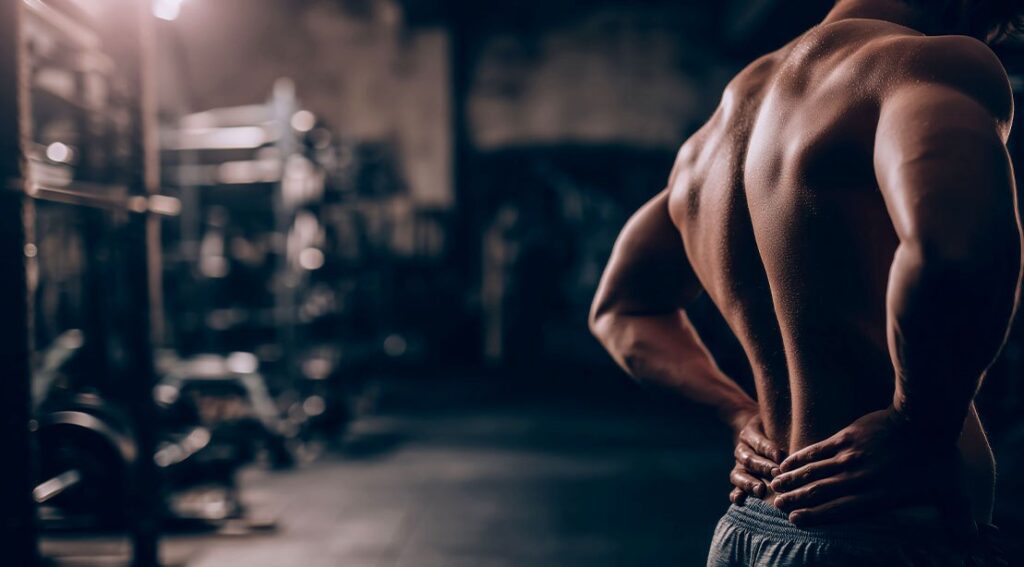 muscular athletic man holding his lower back from fatigue after working out.jpg